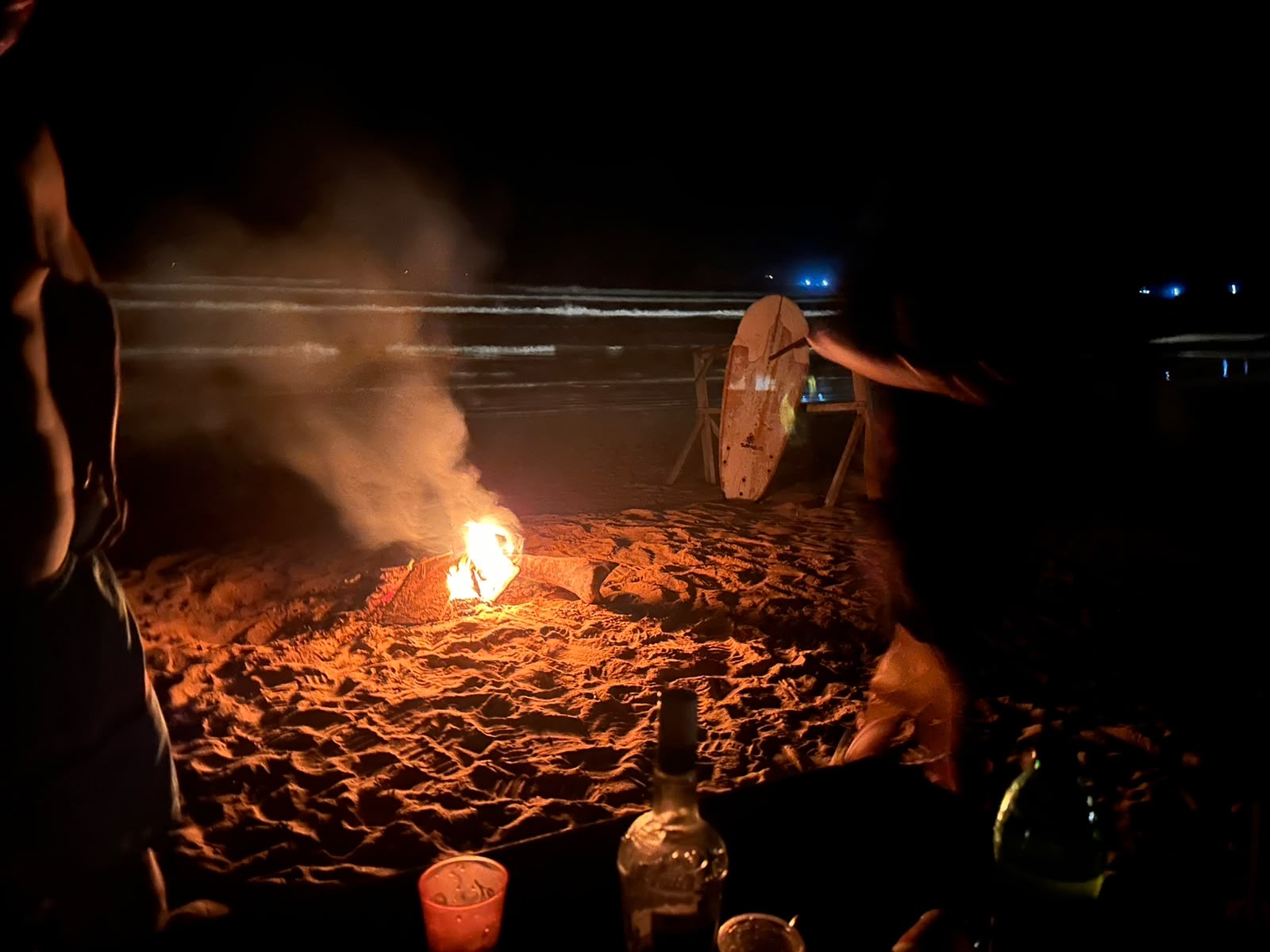 A small beach bonfire beside surfboards at night in Weligama